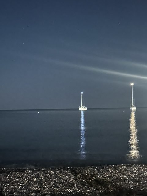 Barche a vela illuminate davanti alla spiaggia di notte